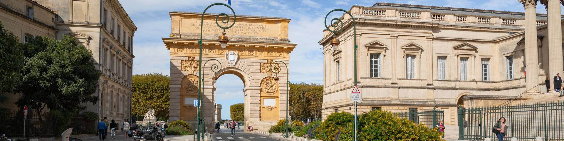 L’Arc de Triomphe à Paris, encadré par des bâtiments de style classique et se dressant sous un ciel dégagé.