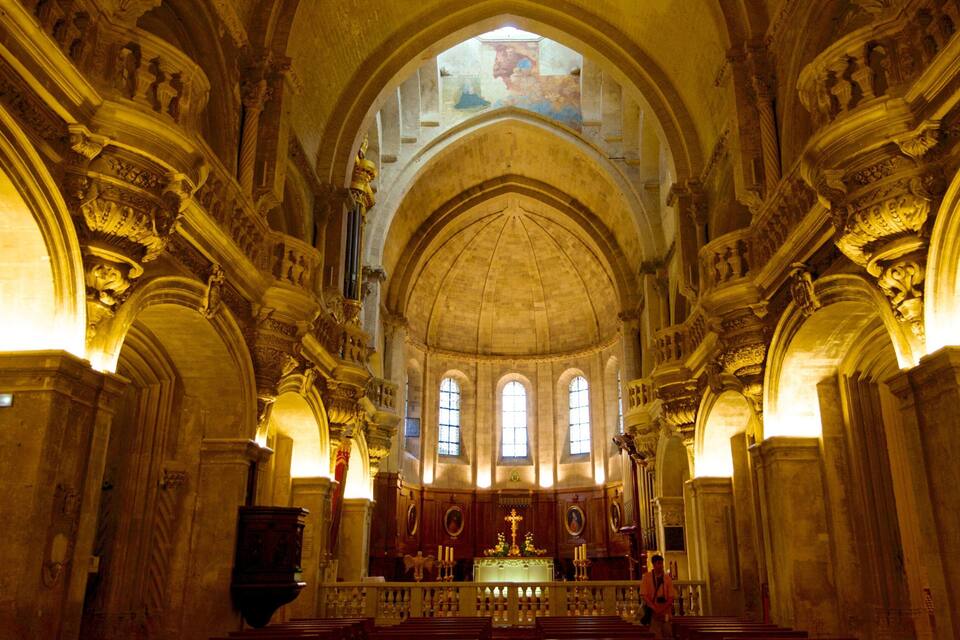 An ornate church interior with high vaulted ceilings, arched windows, and intricate stone carvings.