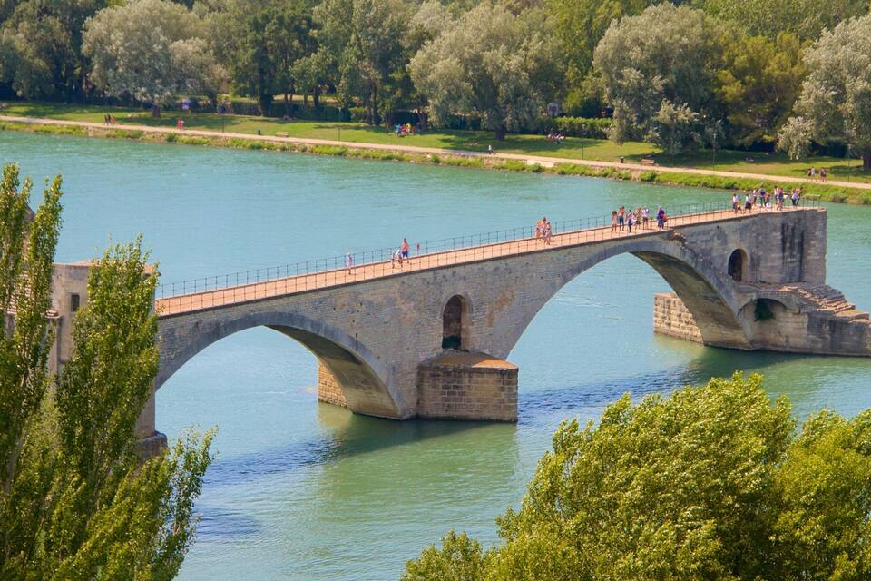 A stone bridge over a river with people walking on it.