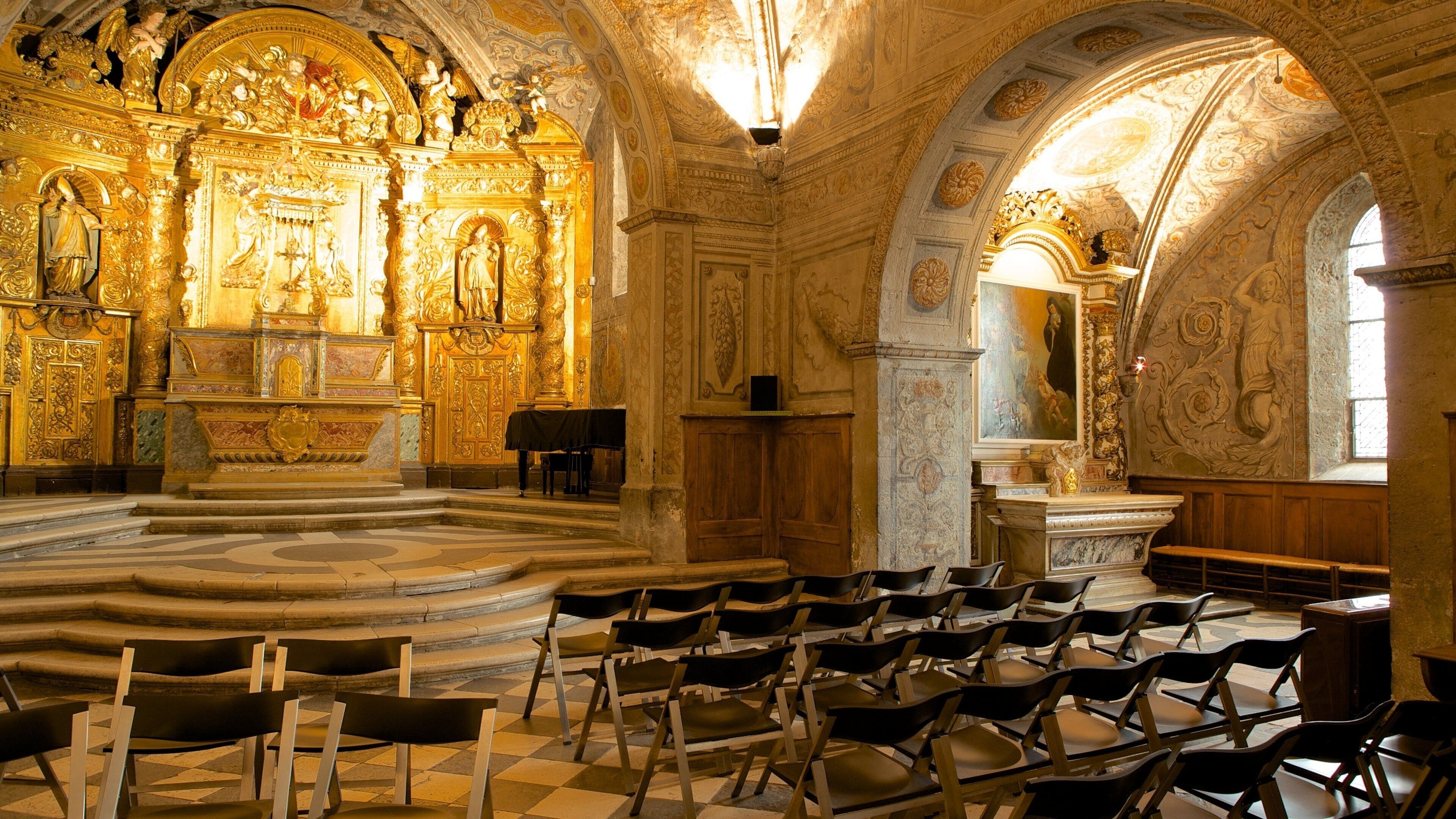 An ornate church interior with golden decorations, a large altar, and rows of chairs.