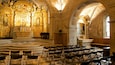 L’intérieur d’une église richement décorée, avec des ornements dorés, un grand autel et des rangées de chaises.