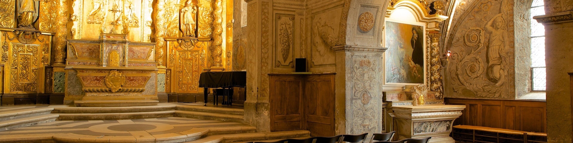 Interior ornamentado de una iglesia con decoraciones doradas, un altar grande y hileras de sillas.