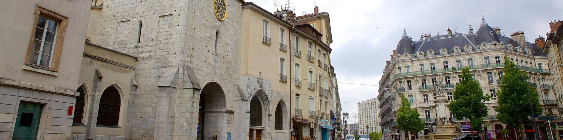 Una plaza histórica con una destacada torre de reloj, una fuente y arquitectura clásica.