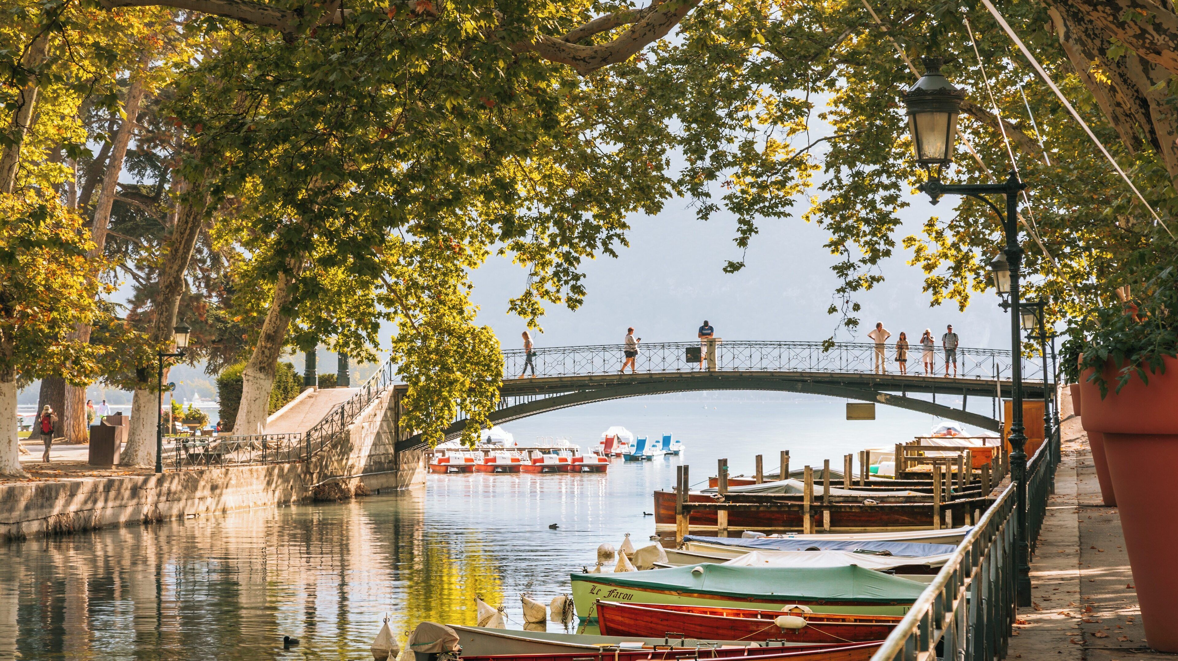 Explore the charm of Amours Bridge in Annecy Old Town, nestled by tranquil waters and vibrant greenery in Auvergne-Rhône-Alpes, France during a sunny day