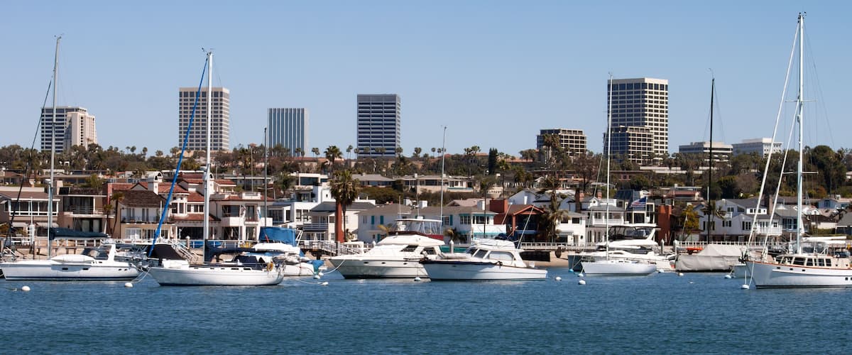 Newport Beach Harbor in California city skyline with boats homes and Fashion Island high rise buildings in the background