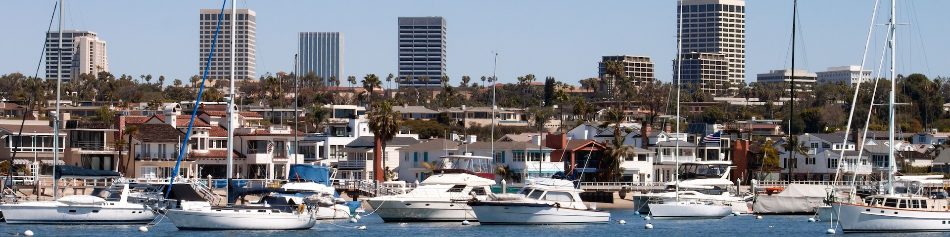 Newport Beach Harbor in California city skyline with boats homes and Fashion Island high rise buildings in the background
