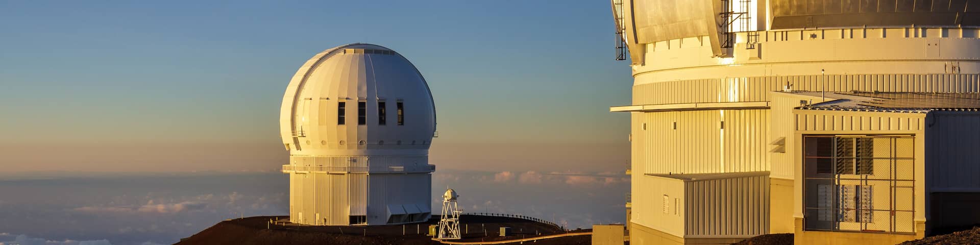 Observatories shining yellow at sunset on the summit of Mauna Kea, Big Island, Hawaii.