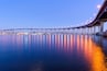 Un pont enjambant une étendue d’eau calme, avec des bateaux et les lumières de la ville qui se reflètent à la surface.