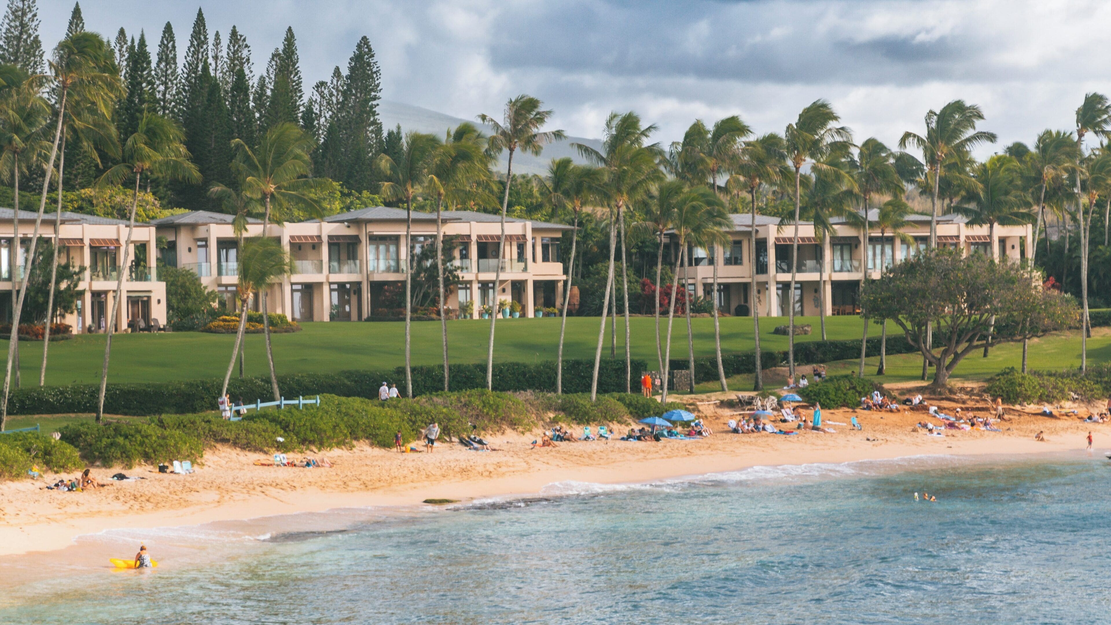Kapalua Beach features golden sand, palm trees, and inviting ocean waves in Lahaina, Hawaii, attracting beachgoers for relaxation and fun
