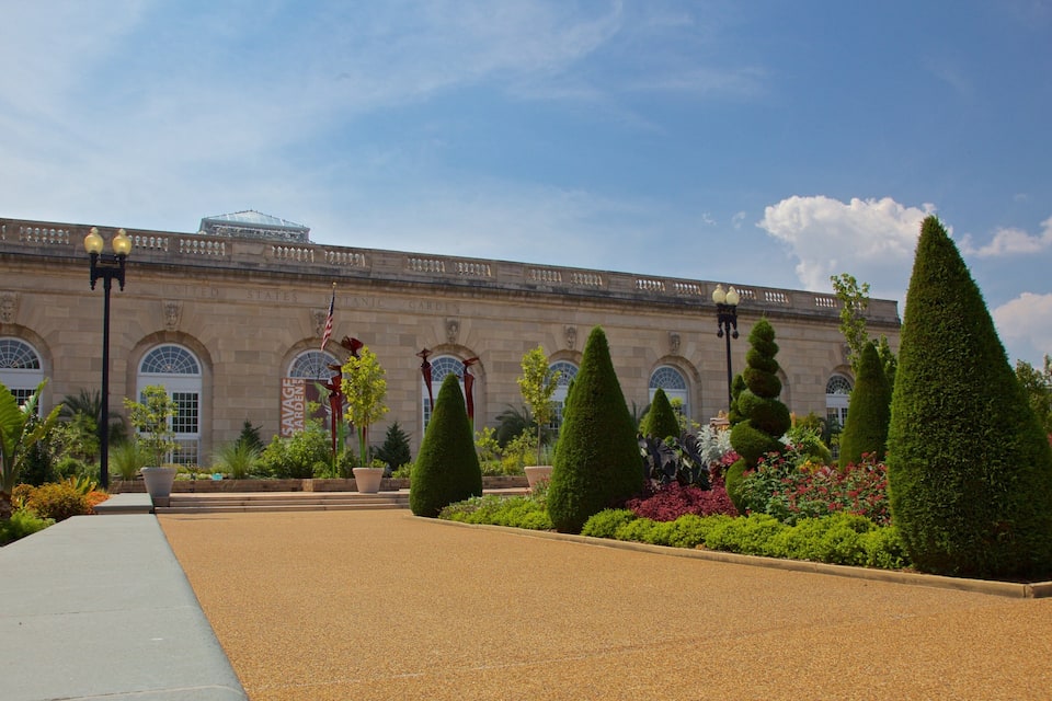 A historic building with a formal garden, including neatly trimmed hedges and a variety of colorful flowers.