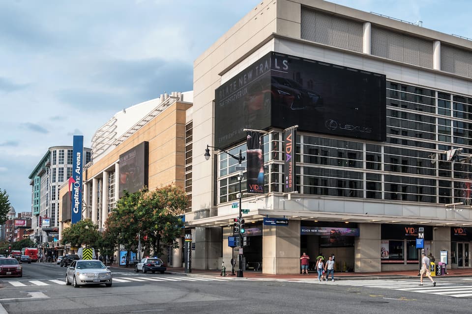 Una calle urbana moderna con un edificio grande que muestra publicidad para Lexus y Vida.