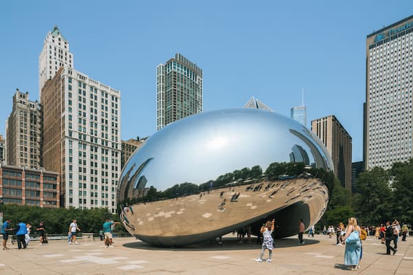 Une grande sculpture sphérique en métal, installée sur une place publique et entourée de bâtiments imposants.