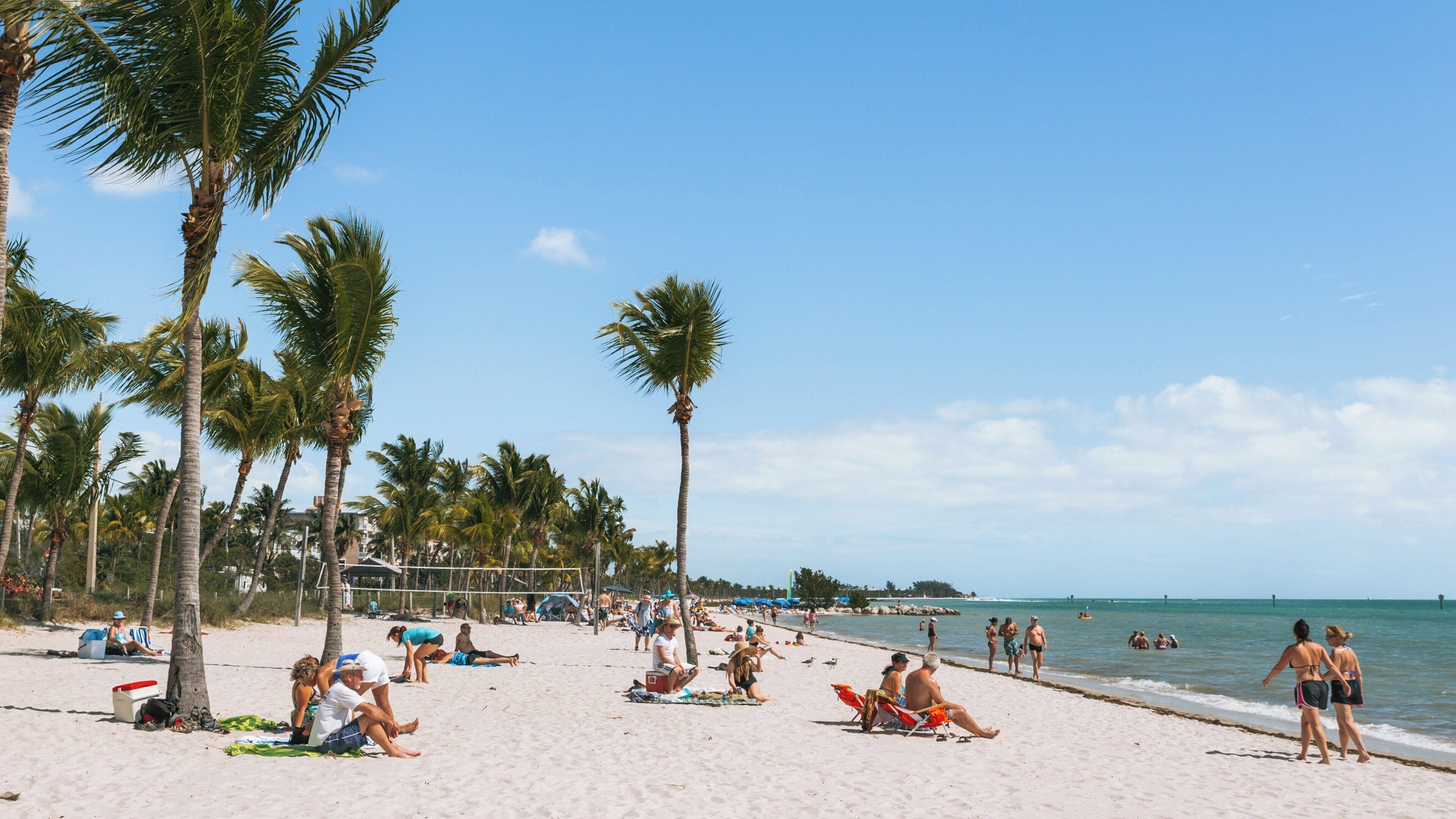 Relaxing day at Smathers Beach, Key West, Florida with sunbathers, beachgoers, and shimmering waters under a clear blue sky