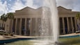 Un grand bâtiment doté de colonnes et orné d’une fontaine à l’avant.