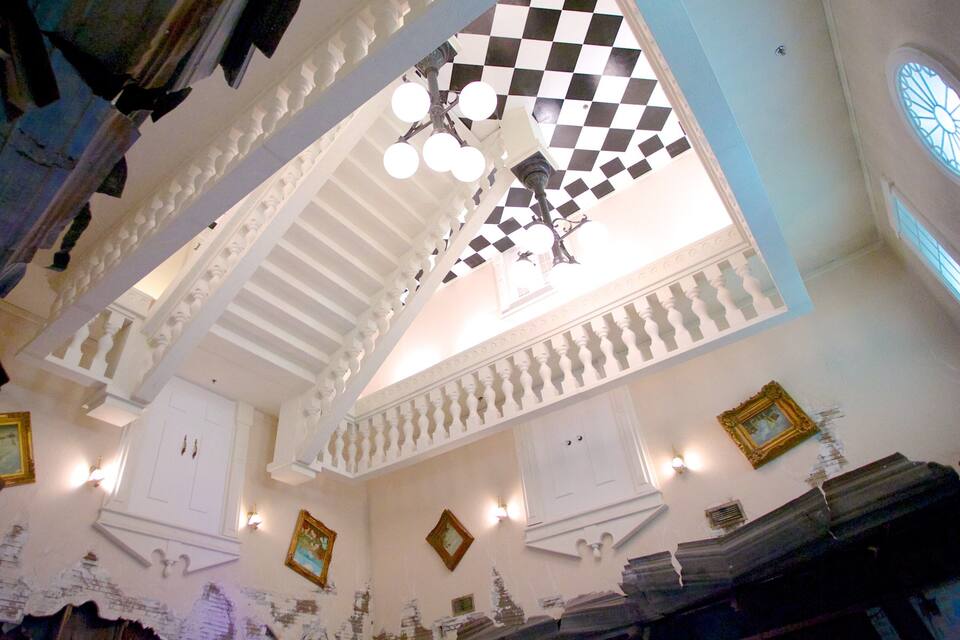 A room with a checkered ceiling, white walls, and a chandelier.