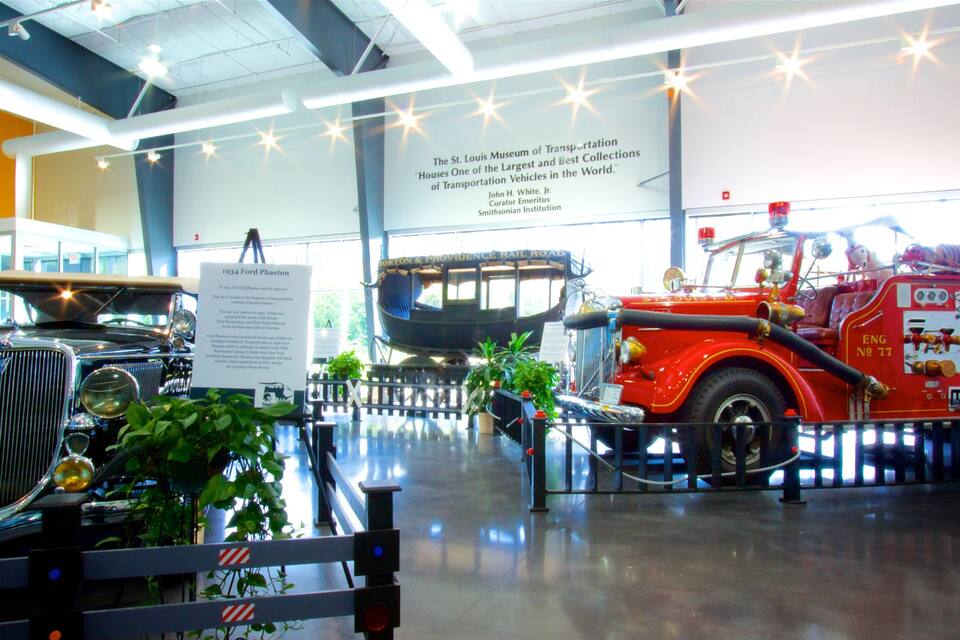Exposição de museu com veículos antigos, incluindo um carro Ford Phalet de 1934 e um caminhão de bombeiros.