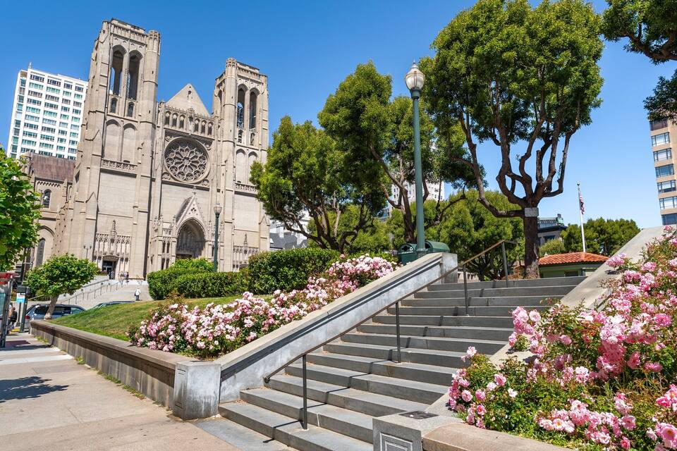 A cathedral with Gothic architecture, a staircase, and blooming pink flowers.