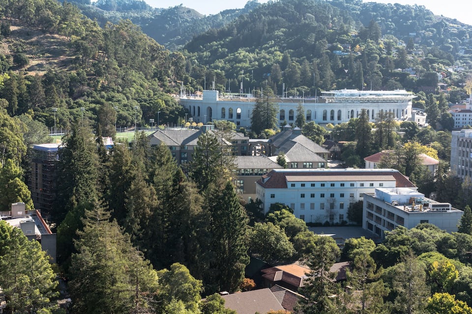 Un paisaje montañoso con un edificio blanco grande rodeado de árboles y otras construcciones.