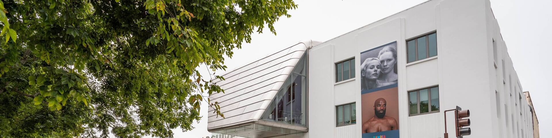 The Art Museum Pacific Film Archive building with a modern design, located at the corner of a street with a traffic light and pedestrians nearby.