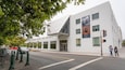 The Art Museum Pacific Film Archive building with a modern design, located at the corner of a street with a traffic light and pedestrians nearby.
