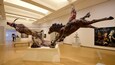 Interior de museo con grandes esculturas de caballos y una figura humana sobre pedestales.