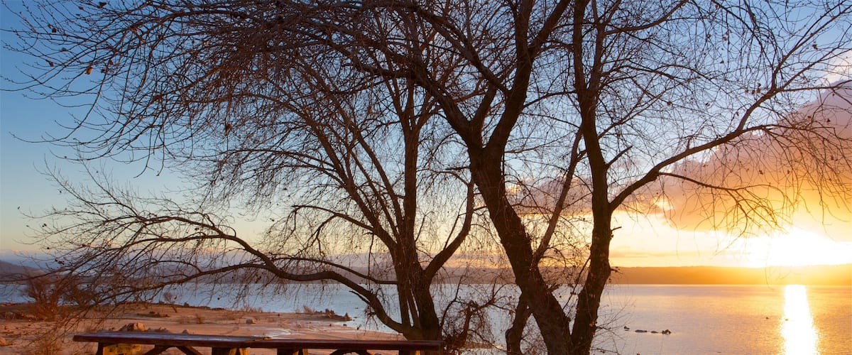 A picnic table by a lake at sunset.