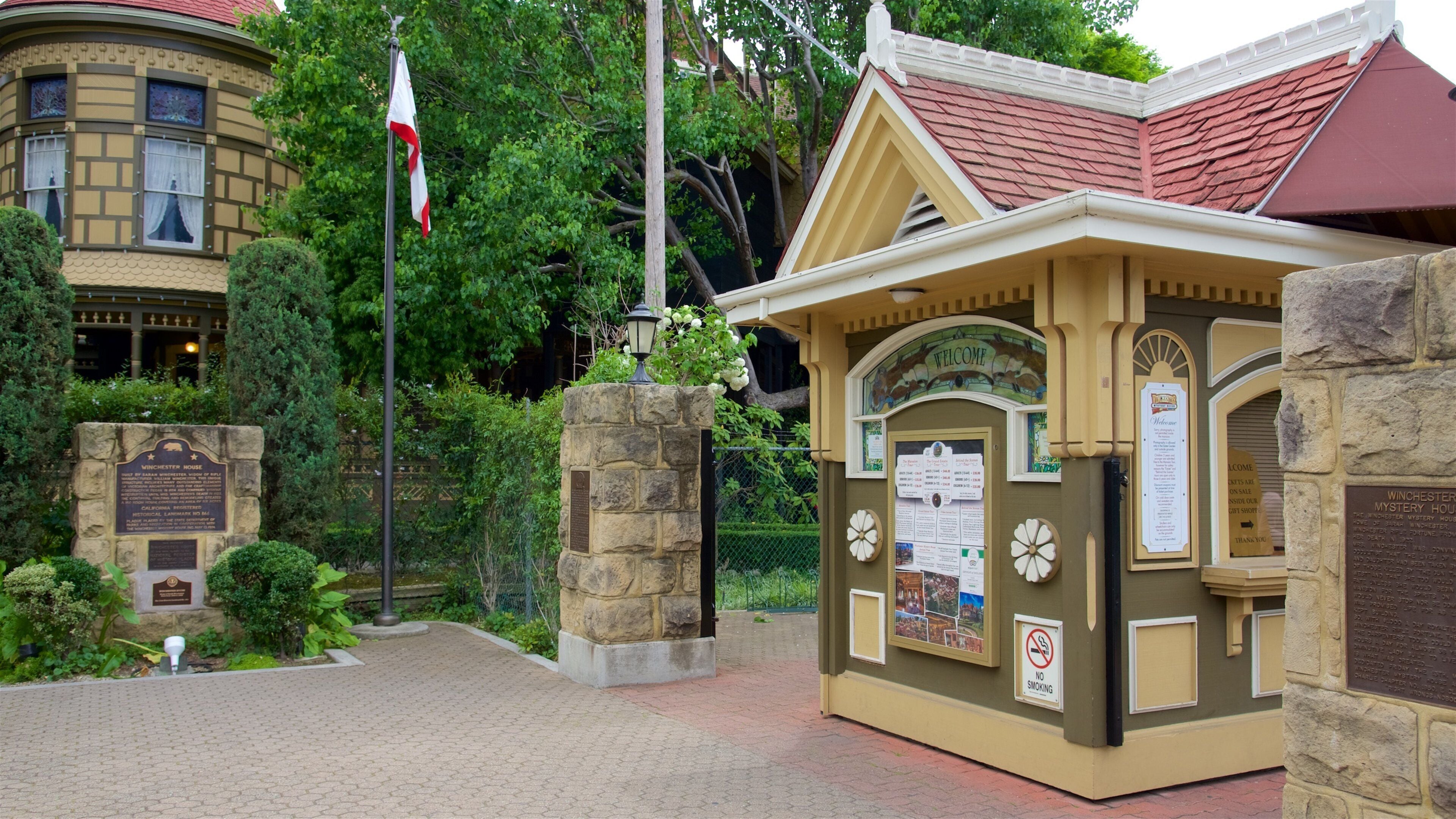 Una casa histórica con entrada de piedra, una bandera y un cartel de bienvenida.