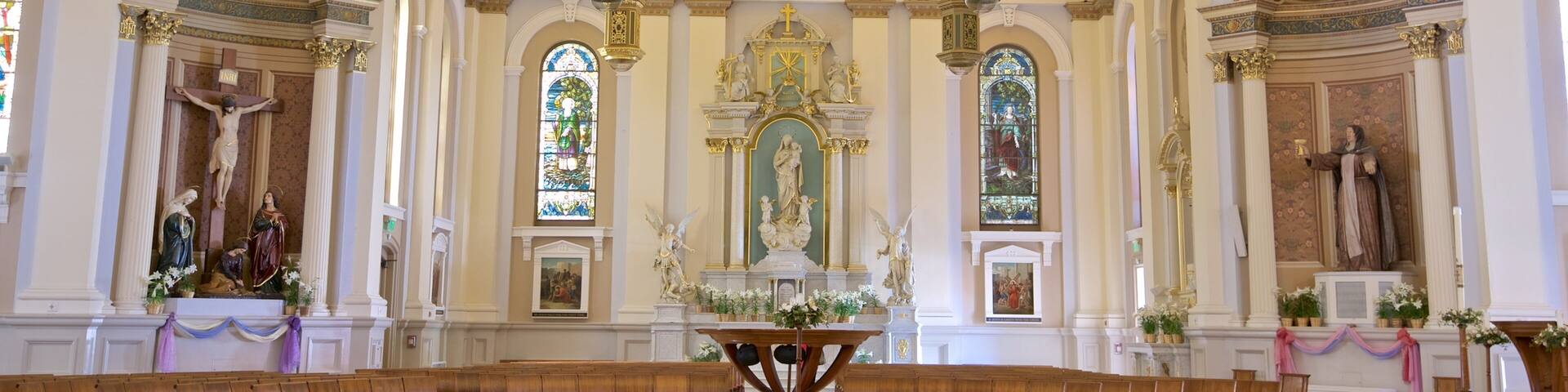 An ornate church interior with a high ceiling, stained glass windows, and religious statues.