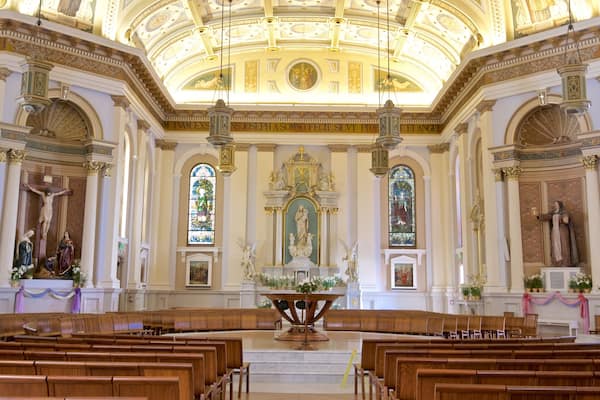 L’intérieur d’une église richement décorée, avec un plafond élevé, des vitraux et des statues religieuses.