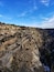 A rugged mountain landscape with layered rock formations and sparse vegetation.
