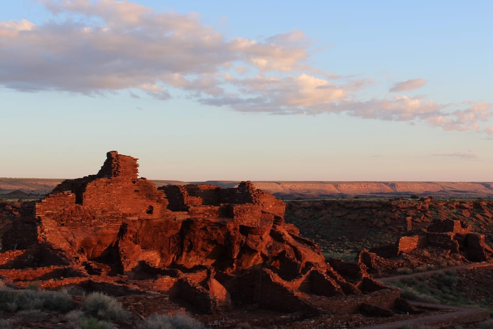 A desert landscape with ancient red rock ruins and a clear sky.