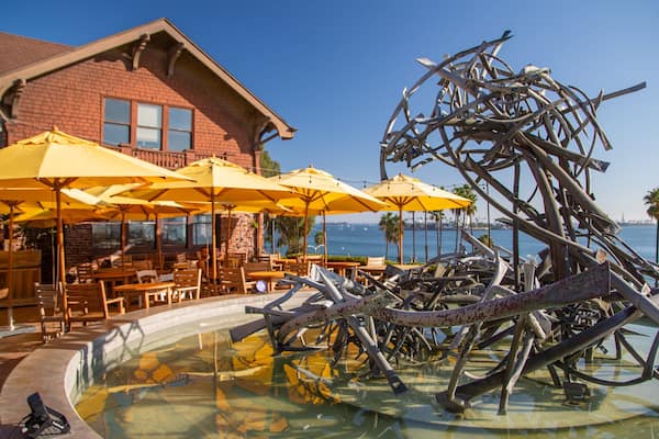 Ein Pool mit Skulptur, Sitzgelegenheiten im Freien und ein Gebäude mit gelben Sonnenschirmen.
