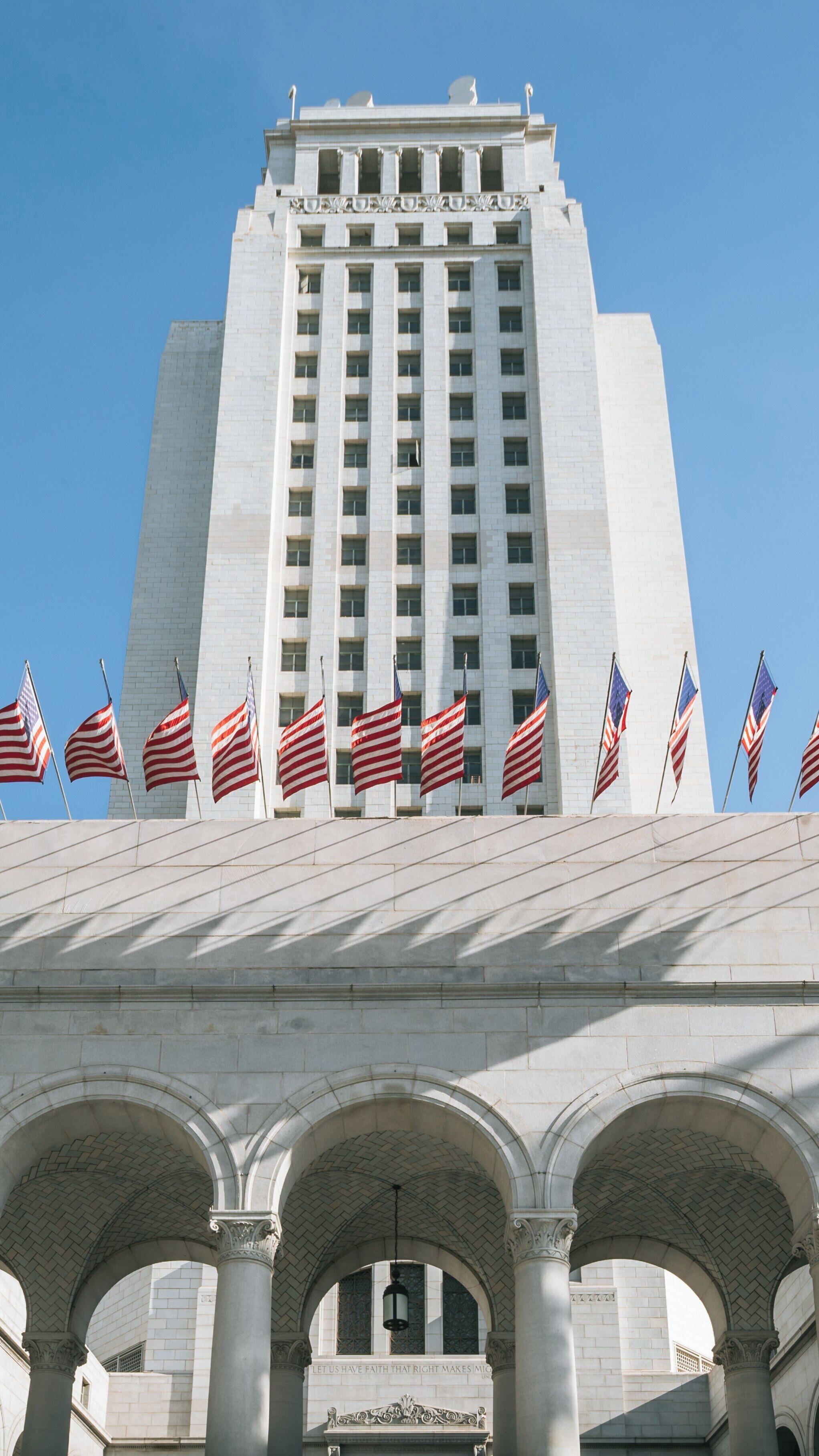 Los Angeles City Hall showcases flags and architecture in Downtown Los Angeles, California on a clear sunny day