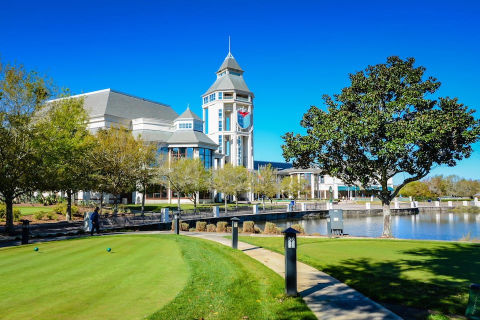 Un campo de golf con un estanque, un puente y un edificio con una torre.