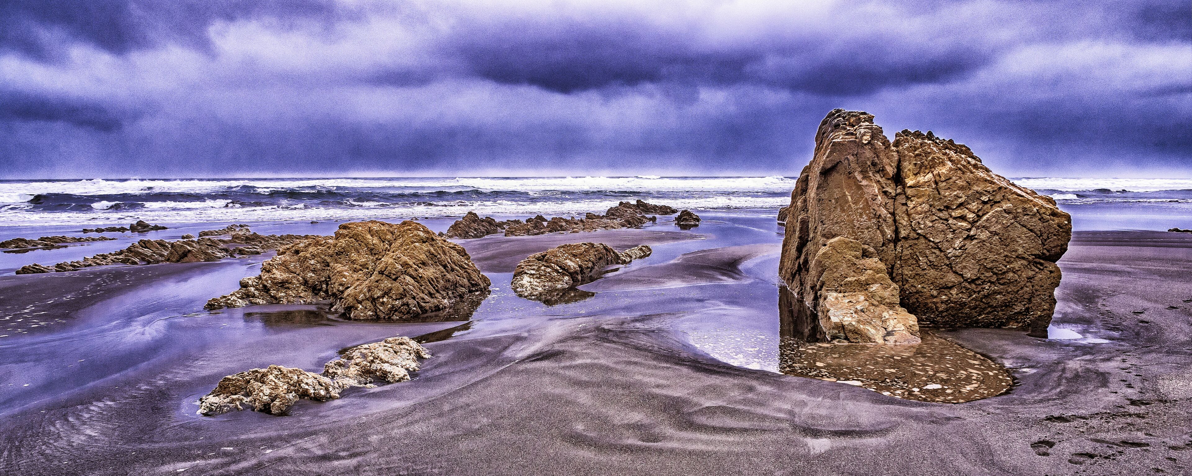 A rocky coastline with large boulders and a stormy sky.