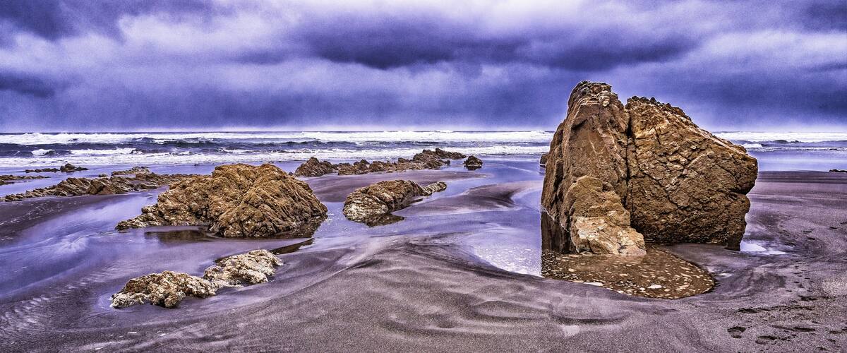 A rocky coastline with large boulders and a stormy sky.