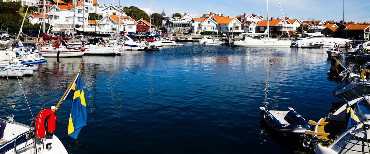 A marina with boats, houses with orange roofs, and a Swedish flag.