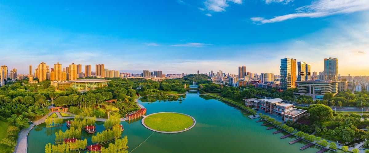 A cityscape with a river, green spaces, and modern high-rise buildings.