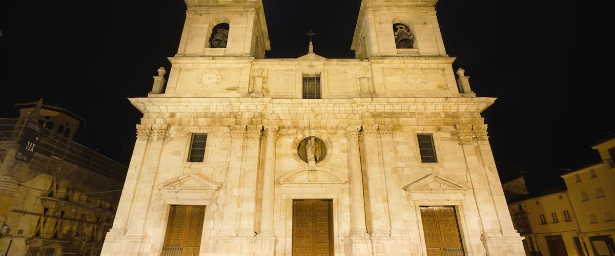 A historic cathedral with two bell towers, large wooden doors, and a central dome.