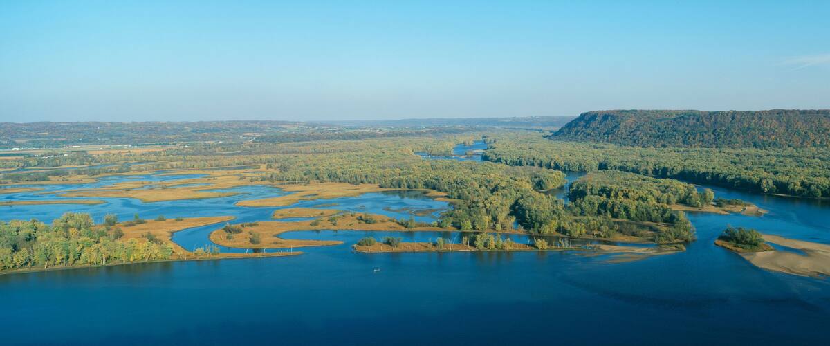 A river winding through a forested landscape with a prominent hill in the background.