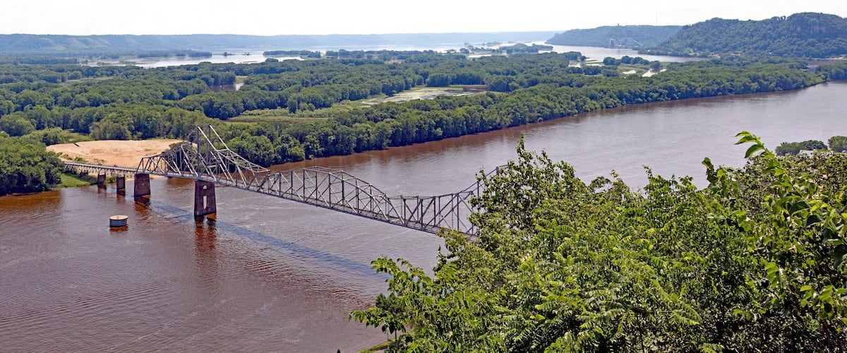 A bridge over a river surrounded by dense forest.