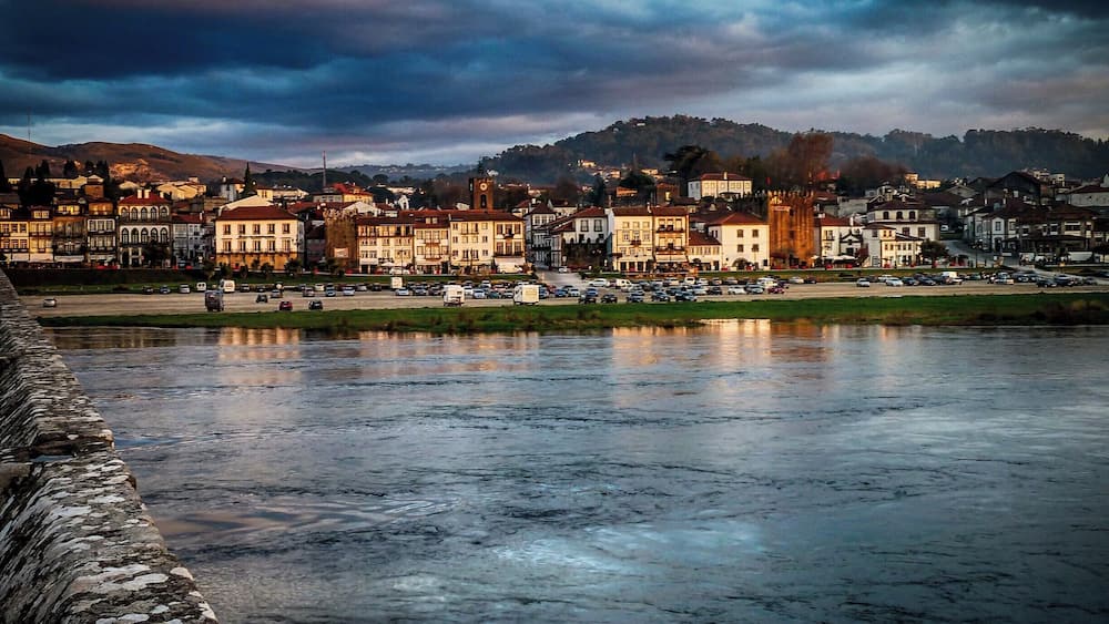 Eine Flussstadt mit historischen Gebäuden und einer Steinmauer.