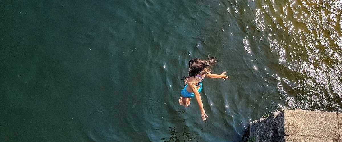 A person diving into a body of water near a stone structure.