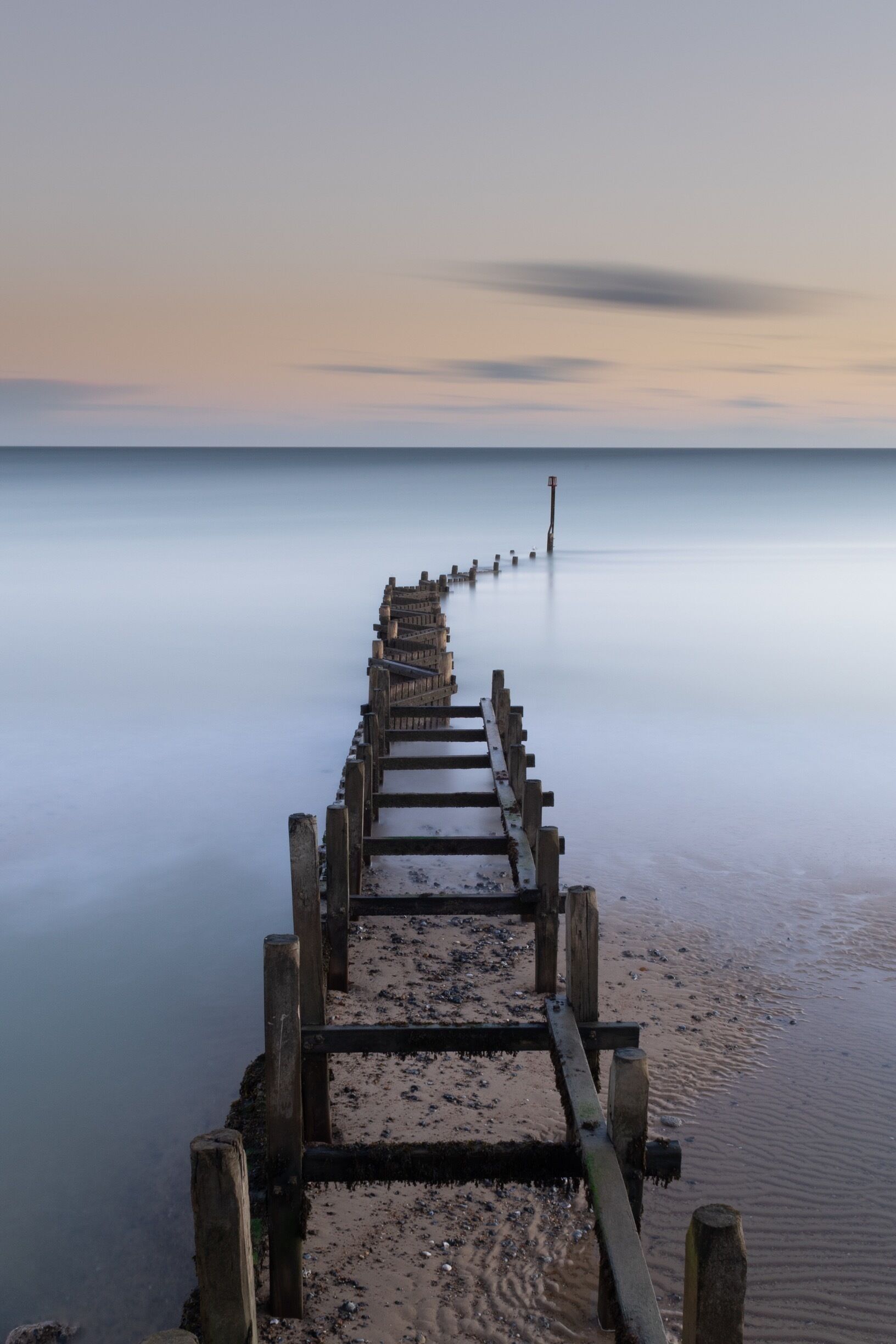 A wooden pier extending into calm waters at sunset.