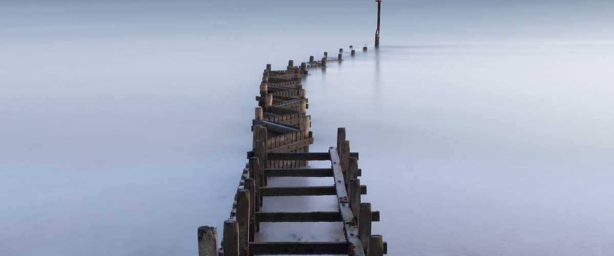 A wooden pier extending into calm waters at sunset.