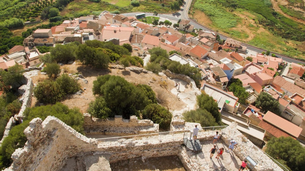 Vue aérienne d’un site archéologique ancien, avec des ruines et des bâtiments modernes.