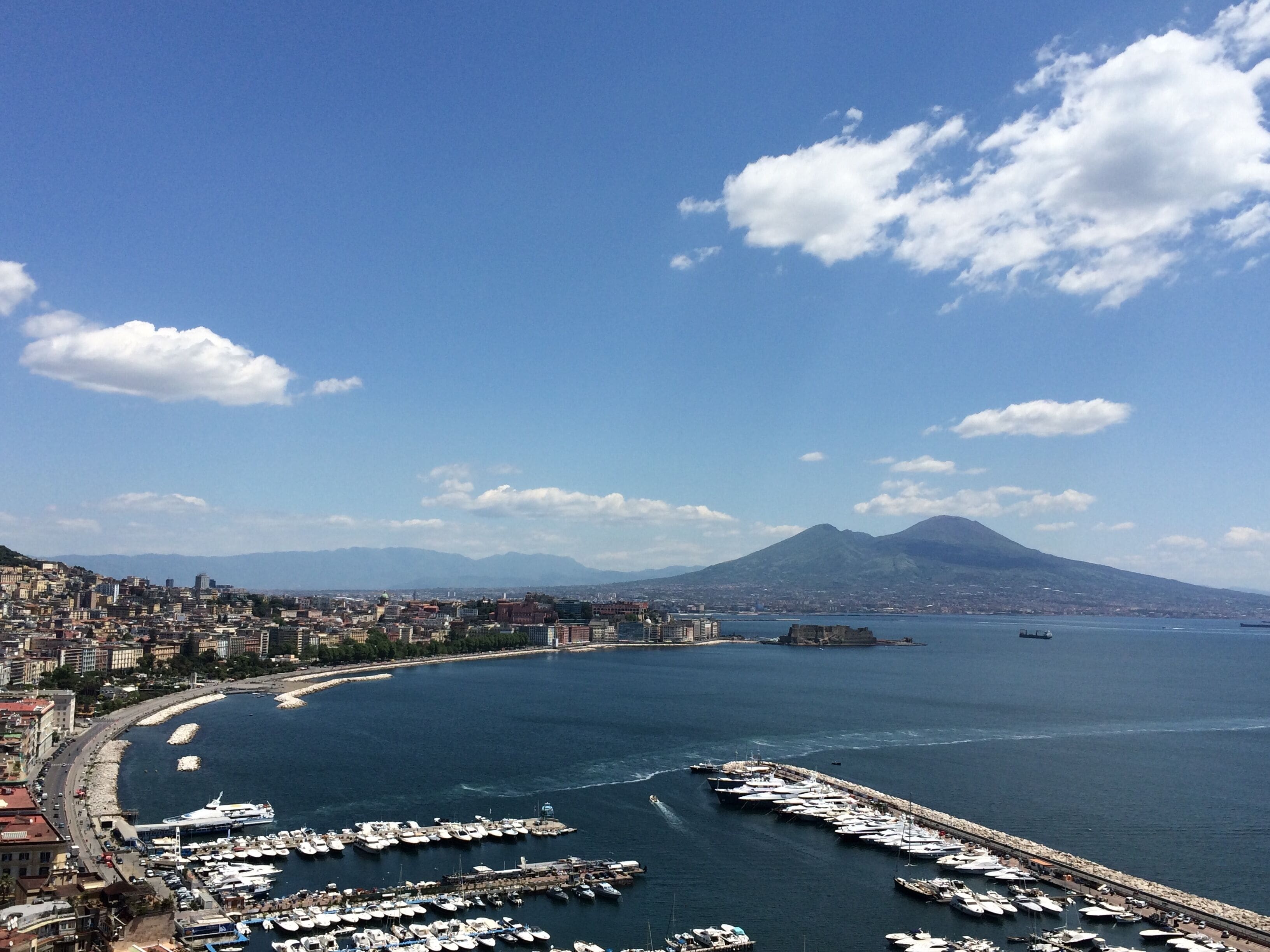Una ciudad costera con un puerto deportivo, montañas y cielo despejado.
