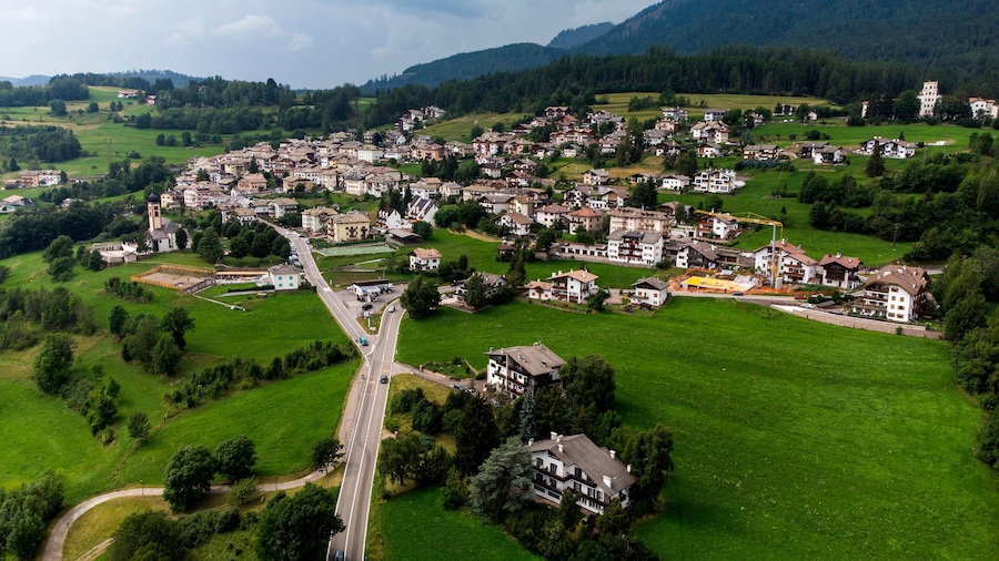 A rural village with houses, a road, and surrounding greenery.