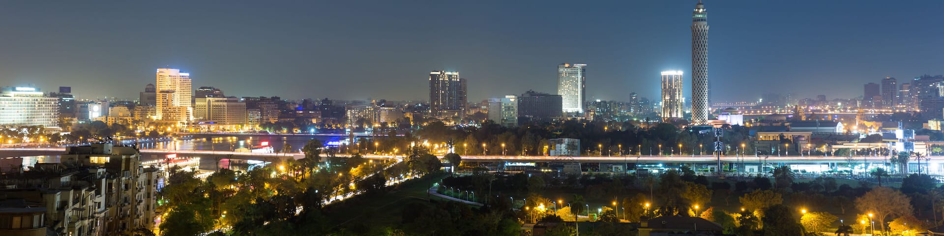 A city skyline at night with illuminated buildings and a prominent tower.