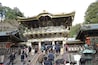A traditional Japanese temple with ornate architecture, a staircase leading to the entrance, and a stone lantern.